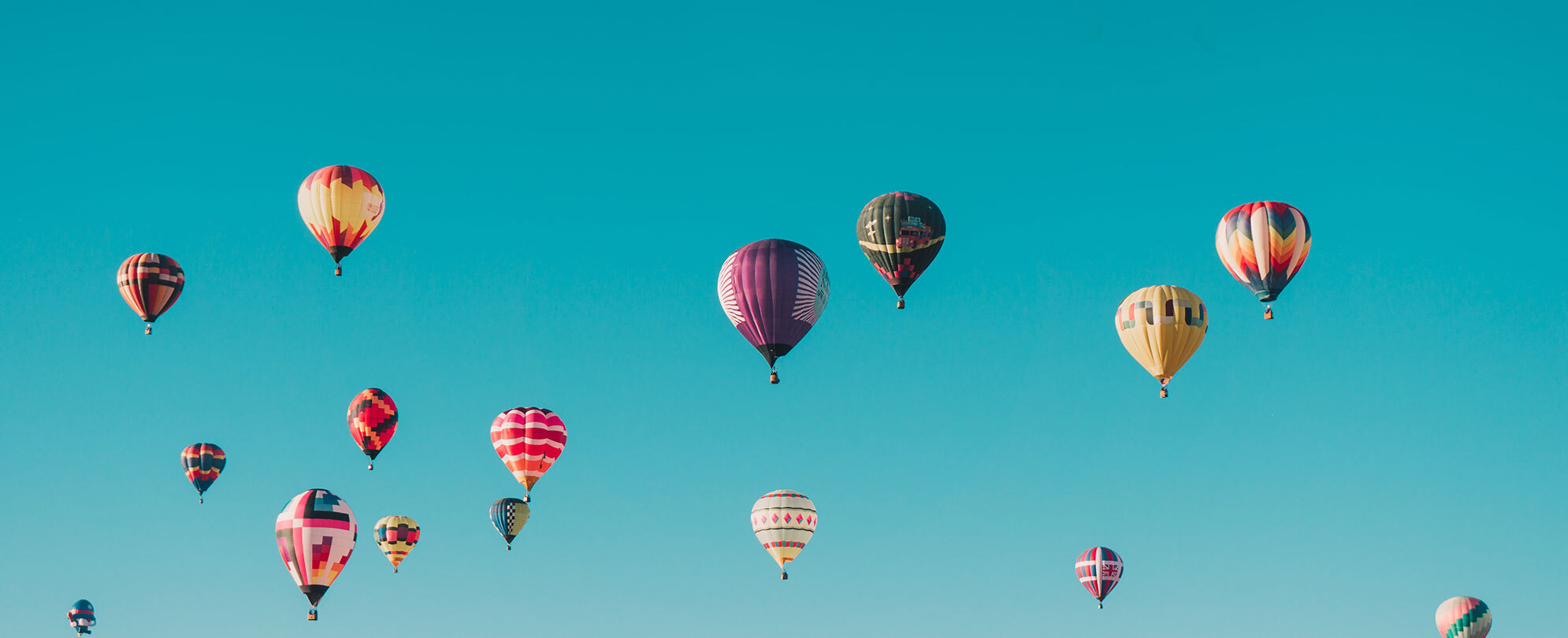 Bright blue sky with different color hot air balloons