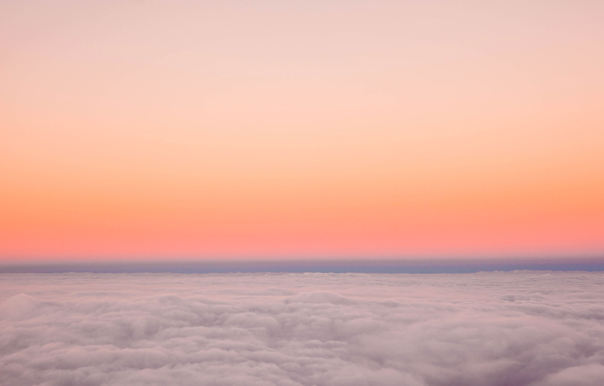 An orange, pink and purple sunset sky from above the clouds 