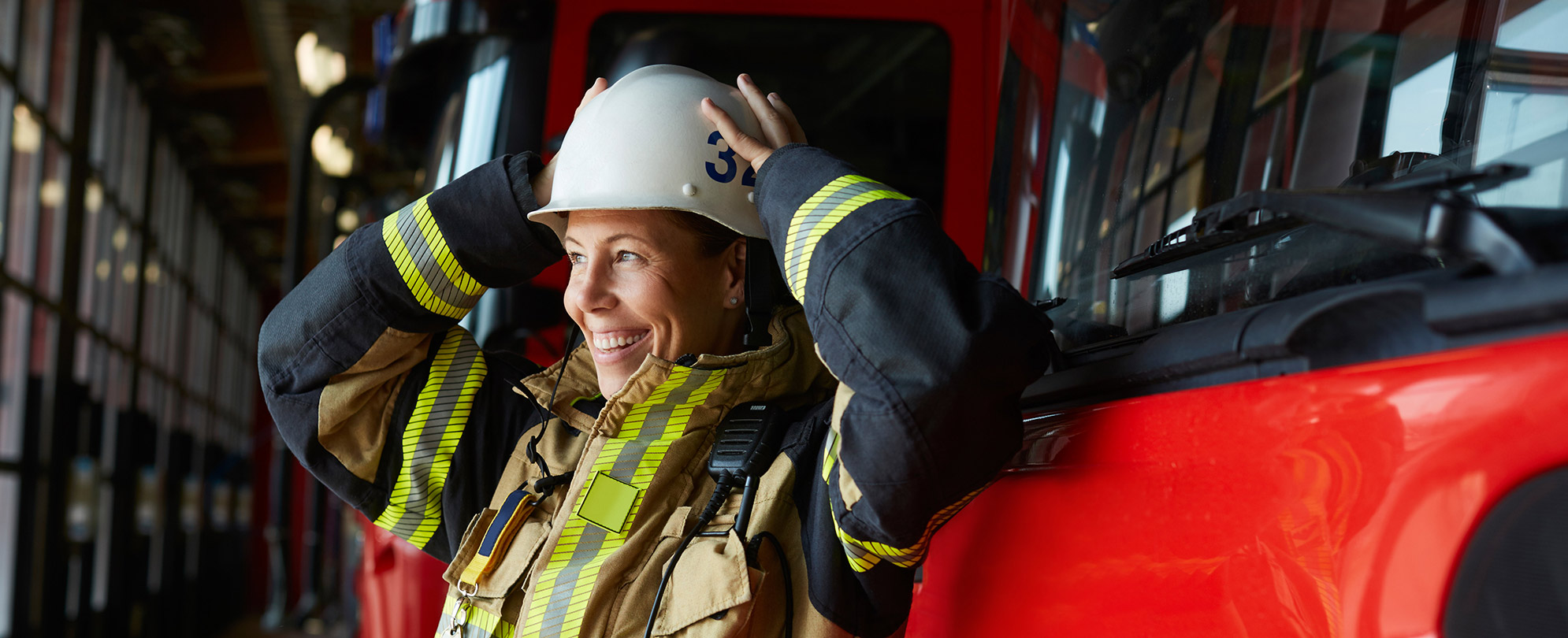 A female firefighter smiling while holding her helmet.